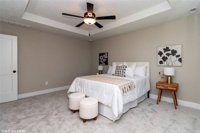 bedroom with a tray ceiling, a textured ceiling, carpet flooring, and ceiling fan