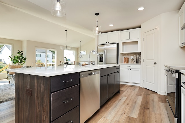 kitchen featuring light hardwood / wood-style floors, white cabinetry, stainless steel appliances, a center island with sink, and dark brown cabinetry