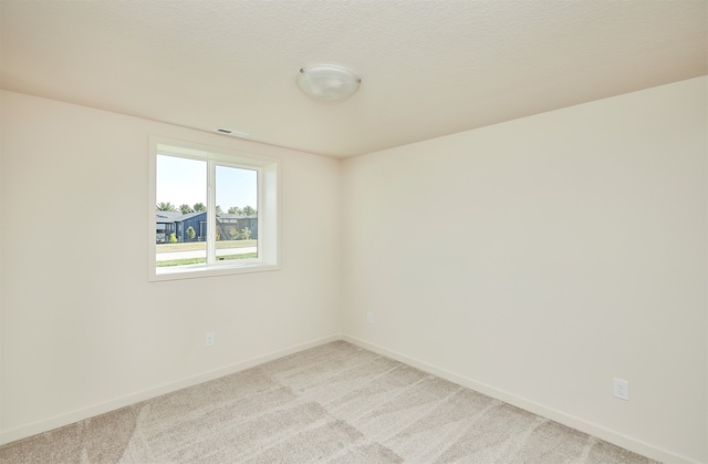 spare room with a textured ceiling and light colored carpet