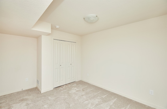 unfurnished bedroom featuring light colored carpet and a closet