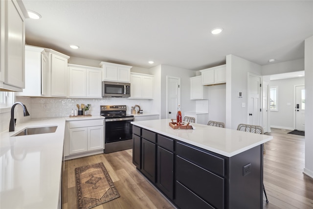 kitchen featuring light hardwood / wood-style floors, appliances with stainless steel finishes, white cabinetry, and a center island