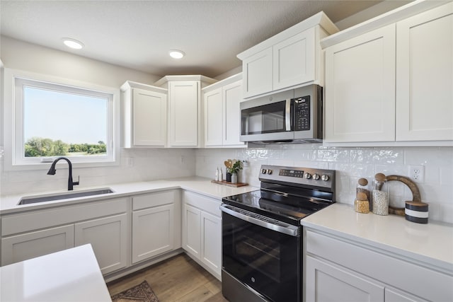 kitchen featuring appliances with stainless steel finishes, backsplash, sink, and white cabinetry