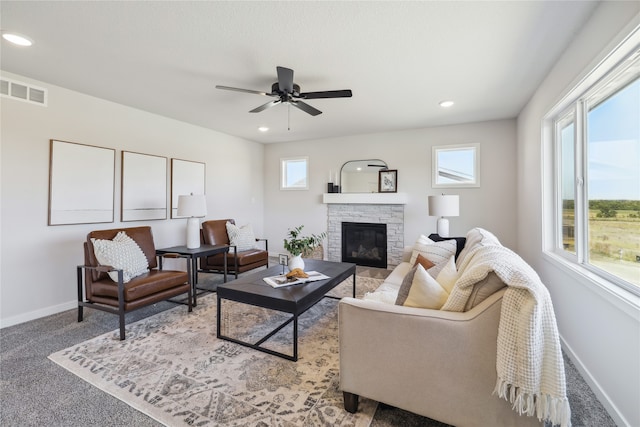 carpeted living room with ceiling fan, a fireplace, and a wealth of natural light