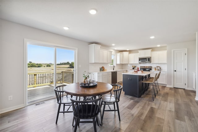 dining space with light hardwood / wood-style flooring and sink