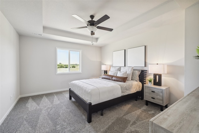 carpeted bedroom featuring a raised ceiling and ceiling fan