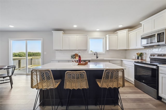 kitchen featuring appliances with stainless steel finishes, a kitchen island, sink, and white cabinetry