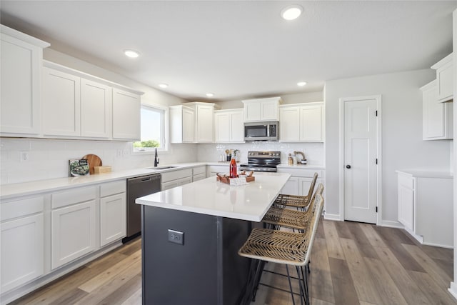 kitchen with appliances with stainless steel finishes, light hardwood / wood-style floors, and white cabinets