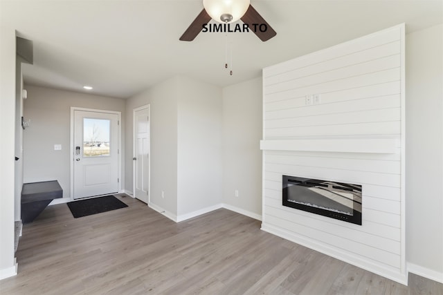 entryway featuring a fireplace, light hardwood / wood-style floors, and ceiling fan