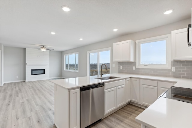 kitchen featuring white cabinetry, sink, kitchen peninsula, light wood-type flooring, and stainless steel dishwasher