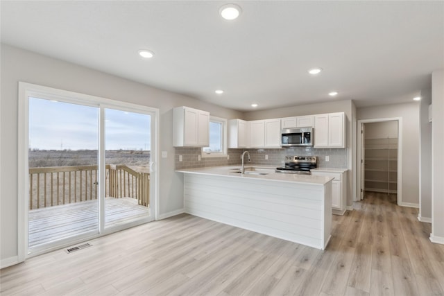 kitchen with kitchen peninsula, white cabinets, and stainless steel appliances