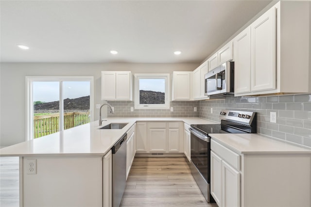 1355 Locust St, Waukee, IA 50263 - kitchen with appliances with stainless steel finishes, a sink, light wood-type flooring, light countertops, and a peninsula