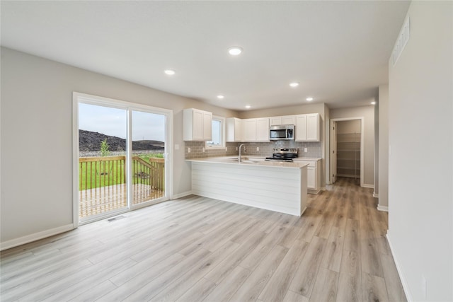 1355 Locust St, Waukee, IA 50263 - kitchen featuring appliances with stainless steel finishes, a sink, light countertops, light wood finished floors, and a peninsula
