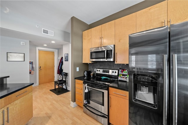 kitchen with tasteful backsplash, light hardwood / wood-style flooring, and appliances with stainless steel finishes