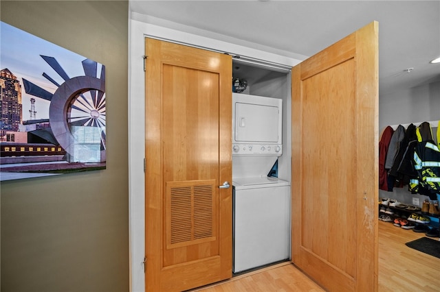 laundry area with stacked washer / dryer and light hardwood / wood-style flooring