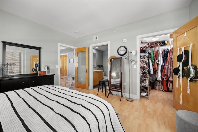 bedroom with a walk in closet, light wood-type flooring, ensuite bathroom, and a closet