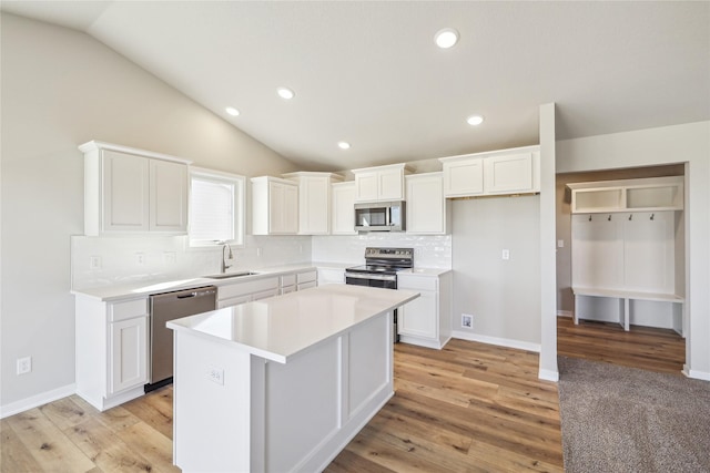 kitchen with a sink, decorative backsplash, white cabinetry, appliances with stainless steel finishes, and a kitchen island