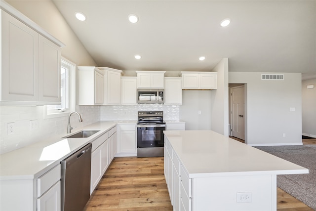 kitchen with sink, a center island, stainless steel appliances, and white cabinetry