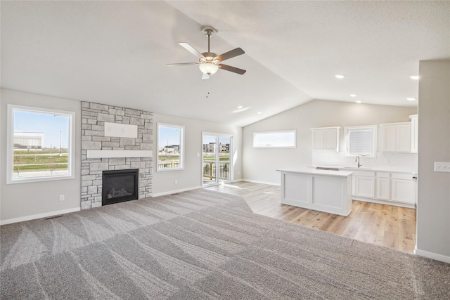 unfurnished living room featuring vaulted ceiling, a sink, ceiling fan, baseboards, and visible vents
