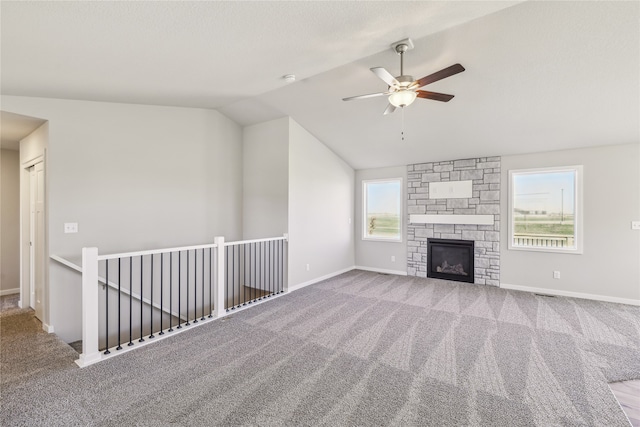 unfurnished living room featuring vaulted ceiling, a healthy amount of sunlight, and carpet floors