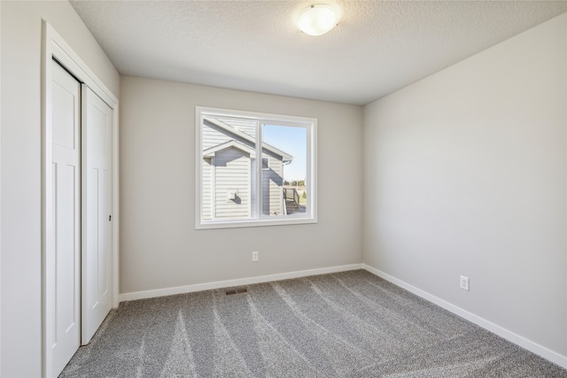 unfurnished bedroom with a closet, a textured ceiling, and carpet flooring