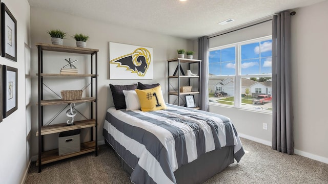 bedroom with a textured ceiling and dark colored carpet