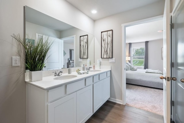 bathroom featuring wood finished floors, double vanity, a sink, and ensuite bathroom