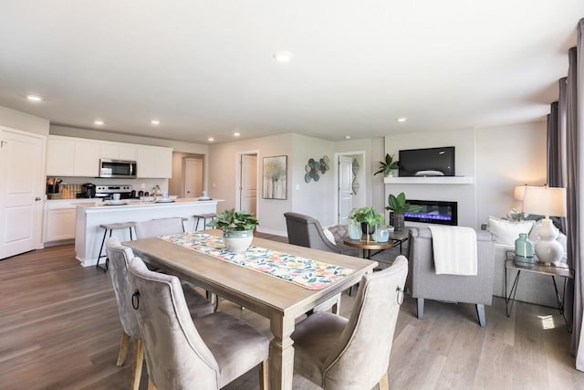 dining room featuring recessed lighting, a glass covered fireplace, and light wood-style floors