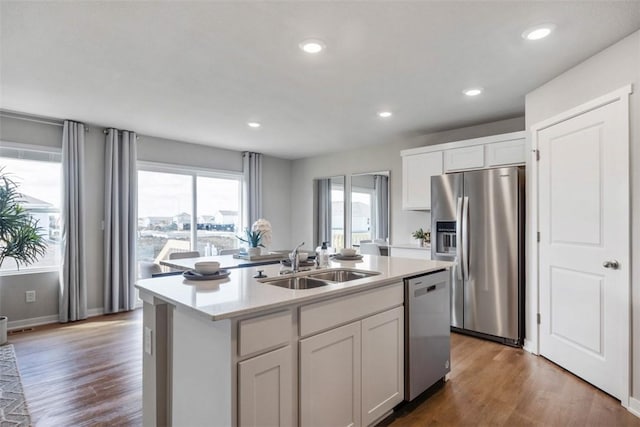 kitchen with stainless steel appliances, a kitchen island with sink, dark wood-type flooring, sink, and white cabinetry