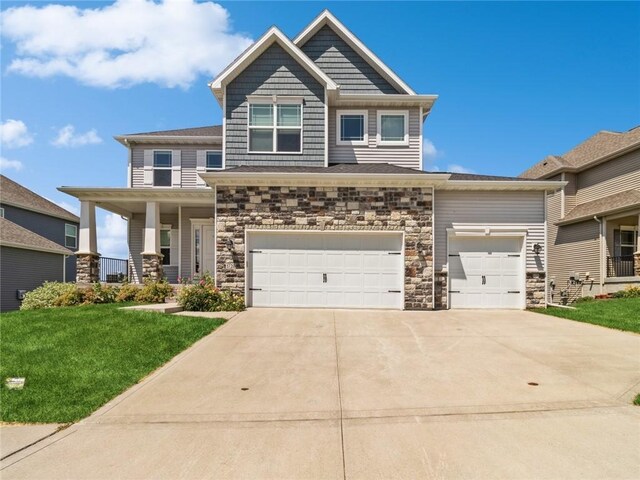 craftsman house featuring covered porch, a garage, and a front lawn