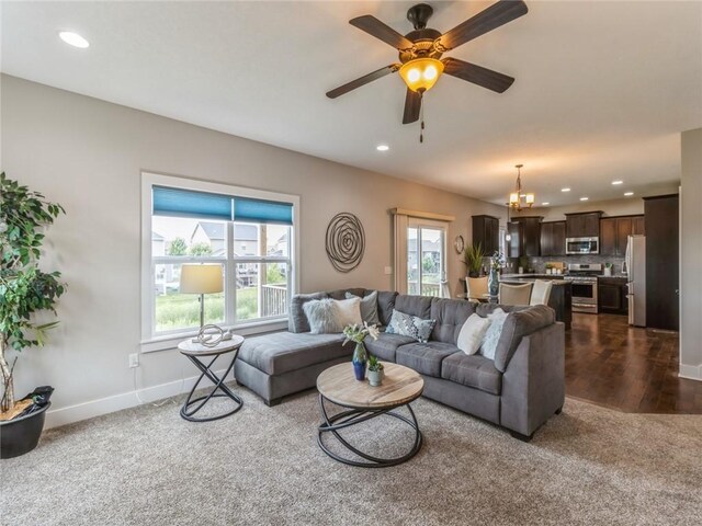 carpeted living room featuring ceiling fan with notable chandelier