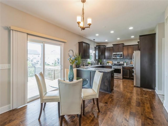 dining space featuring sink, dark wood-type flooring, and a chandelier