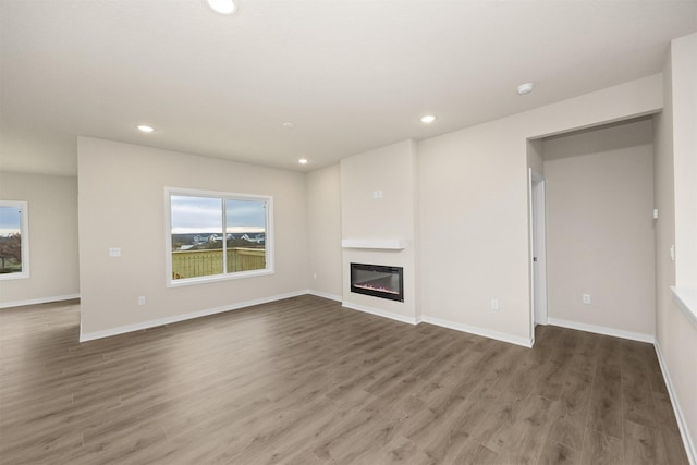 9020 Mockingbird Dr, West Des Moines, IA 50266 - unfurnished living room with healthy amount of natural light, recessed lighting, wood finished floors, a glass covered fireplace, and baseboards