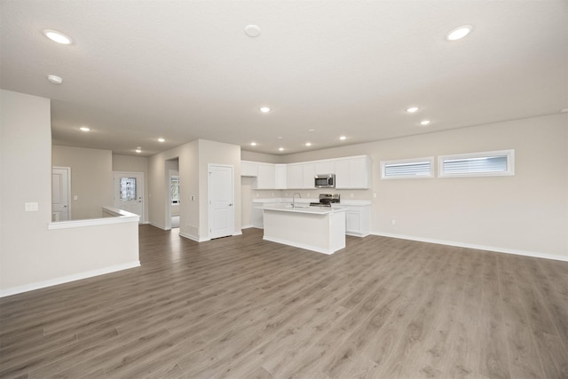 9020 Mockingbird Dr, West Des Moines, IA 50266 - unfurnished living room featuring baseboards, wood finished floors, recessed lighting, and a sink