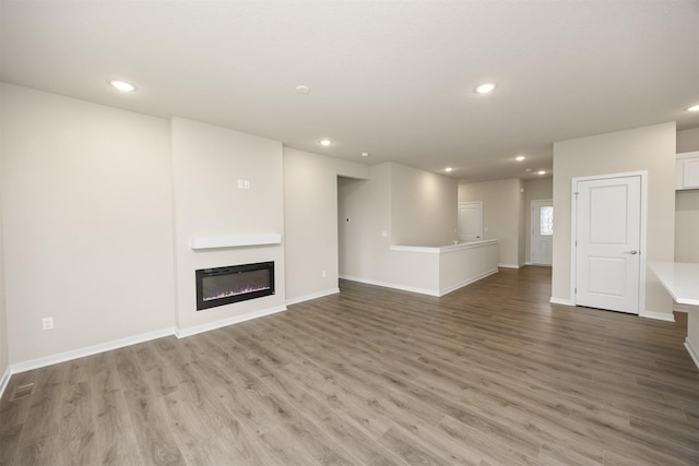9020 Mockingbird Dr, West Des Moines, IA 50266 - unfurnished living room with recessed lighting, wood finished floors, baseboards, and a glass covered fireplace