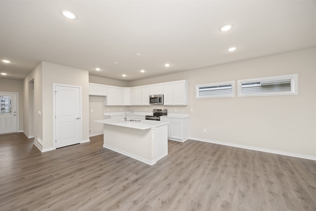 kitchen featuring white cabinetry, sink, light hardwood / wood-style floors, a kitchen island with sink, and appliances with stainless steel finishes