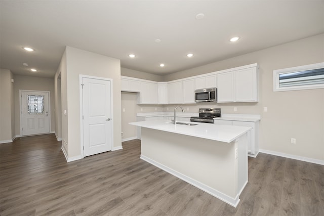 kitchen featuring stainless steel appliances, light hardwood / wood-style floors, a center island with sink, and sink