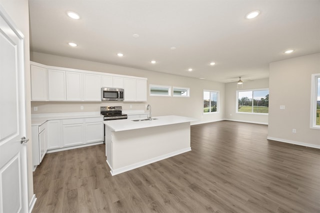 9020 Mockingbird Dr, West Des Moines, IA 50266 - kitchen with stainless steel appliances, a sink, recessed lighting, wood finished floors, and white cabinets
