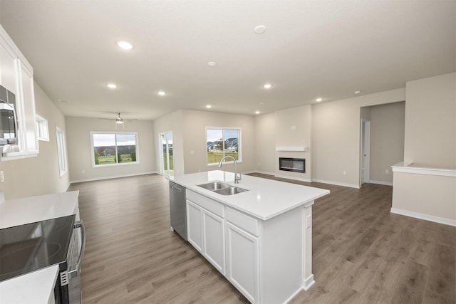 9020 Mockingbird Dr, West Des Moines, IA 50266 - kitchen featuring open floor plan, a sink, dishwasher, white cabinets, and a glass covered fireplace