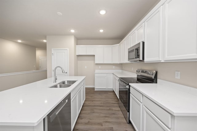 9020 Mockingbird Dr, West Des Moines, IA 50266 - kitchen featuring stainless steel appliances, a sink, recessed lighting, wood finished floors, and white cabinetry