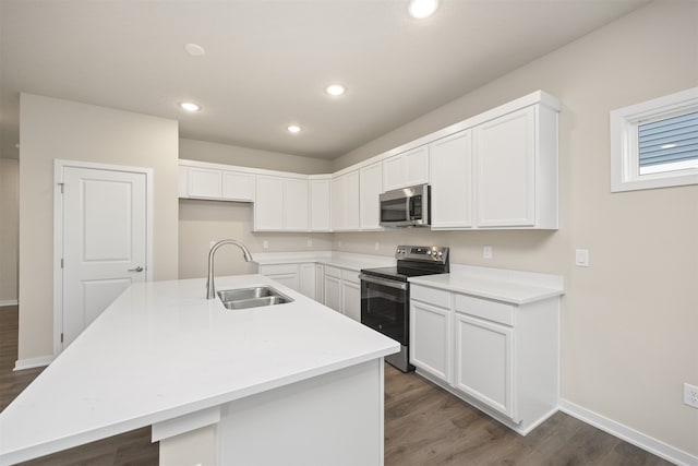 kitchen with a center island with sink, sink, appliances with stainless steel finishes, dark hardwood / wood-style flooring, and white cabinetry