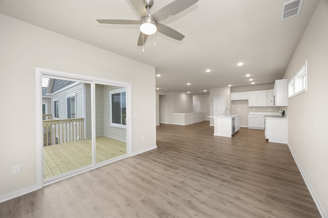 unfurnished living room with ceiling fan, sink, and hardwood / wood-style flooring