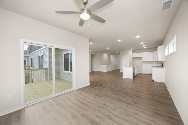 9020 Mockingbird Dr, West Des Moines, IA 50266 - unfurnished living room featuring a sink, light wood-style flooring, baseboards, a ceiling fan, and recessed lighting