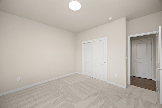 unfurnished bedroom with light colored carpet and a closet