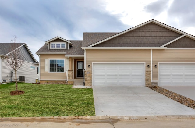 9020 Mockingbird Dr, West Des Moines, IA 50266 - craftsman-style house featuring concrete driveway, stone siding, a front yard, central air condition unit, and roof with shingles
