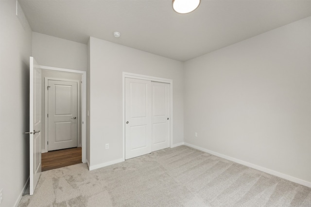 unfurnished bedroom featuring light carpet and a closet