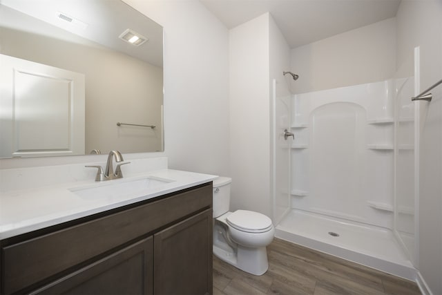 bathroom with a shower, toilet, vanity, and hardwood / wood-style flooring