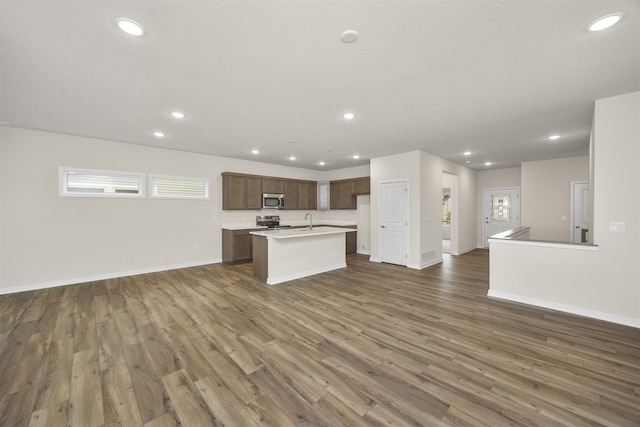 kitchen featuring dark hardwood / wood-style floors, sink, stainless steel appliances, and an island with sink