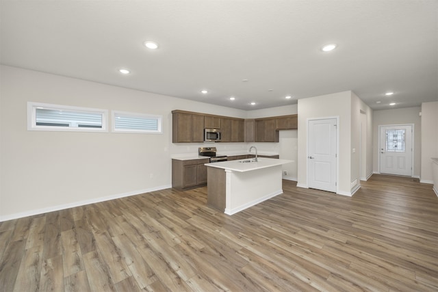 kitchen featuring sink, a center island with sink, light hardwood / wood-style floors, and appliances with stainless steel finishes