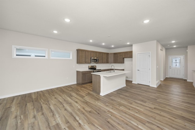 9042 Mockingbird Dr, West Des Moines, IA 50266 - kitchen with stainless steel appliances, a sink, light wood-style floors, recessed lighting, and an island with sink
