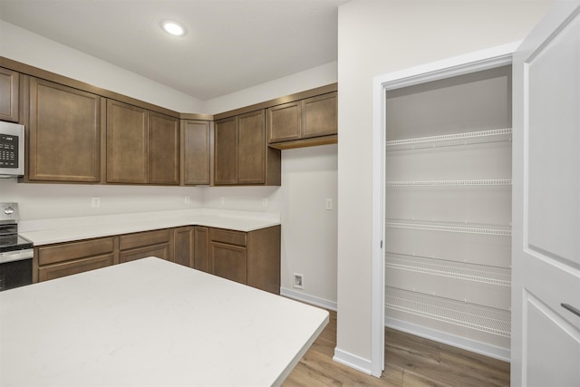 9042 Mockingbird Dr, West Des Moines, IA 50266 - kitchen with light wood finished floors, light countertops, stainless steel electric stove, baseboards, and white microwave